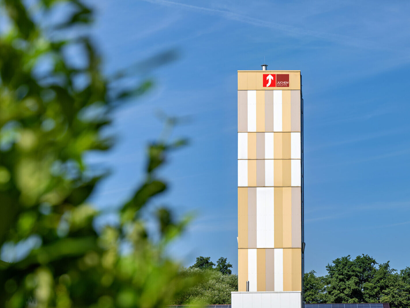 JUCHEM Gruppe striped tower with logo against blue sky and greenery background