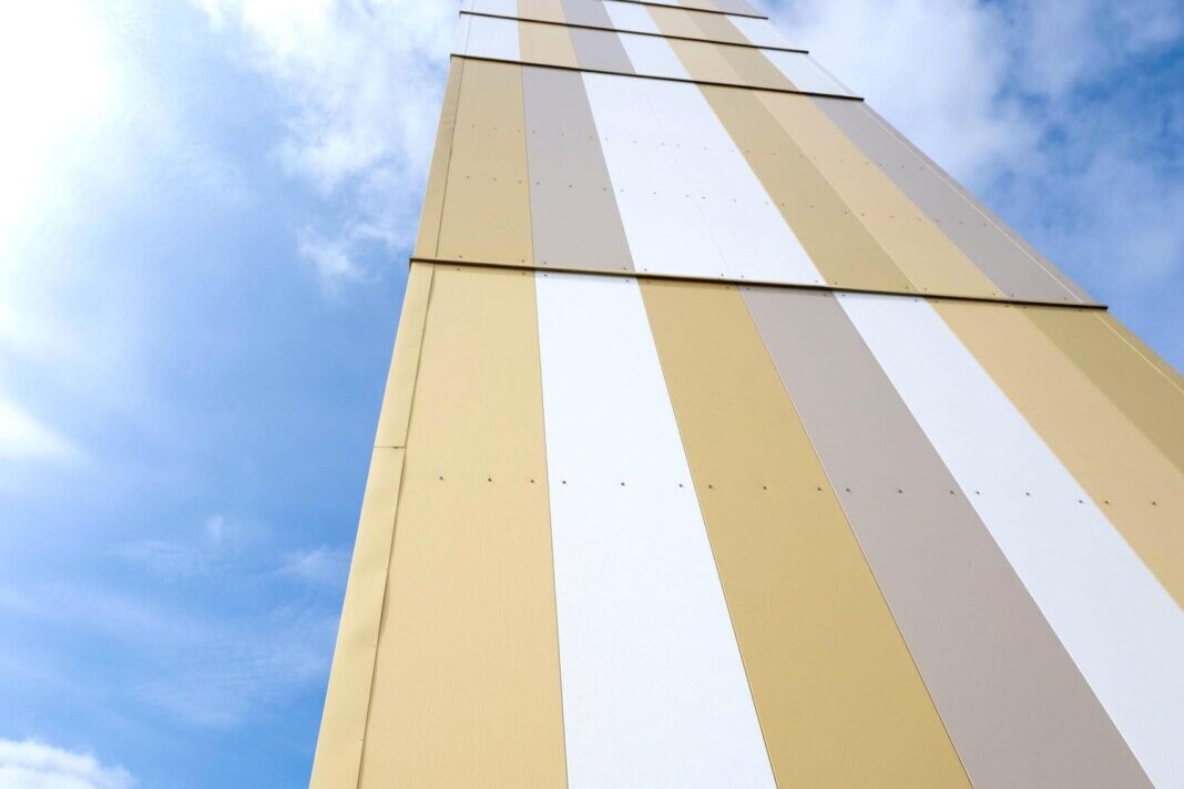 Modern striped commercial building facade against a blue sky with clouds