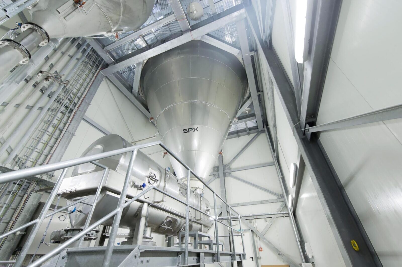 SPX industrial mixing tank with stainless steel piping inside large chemical processing facility