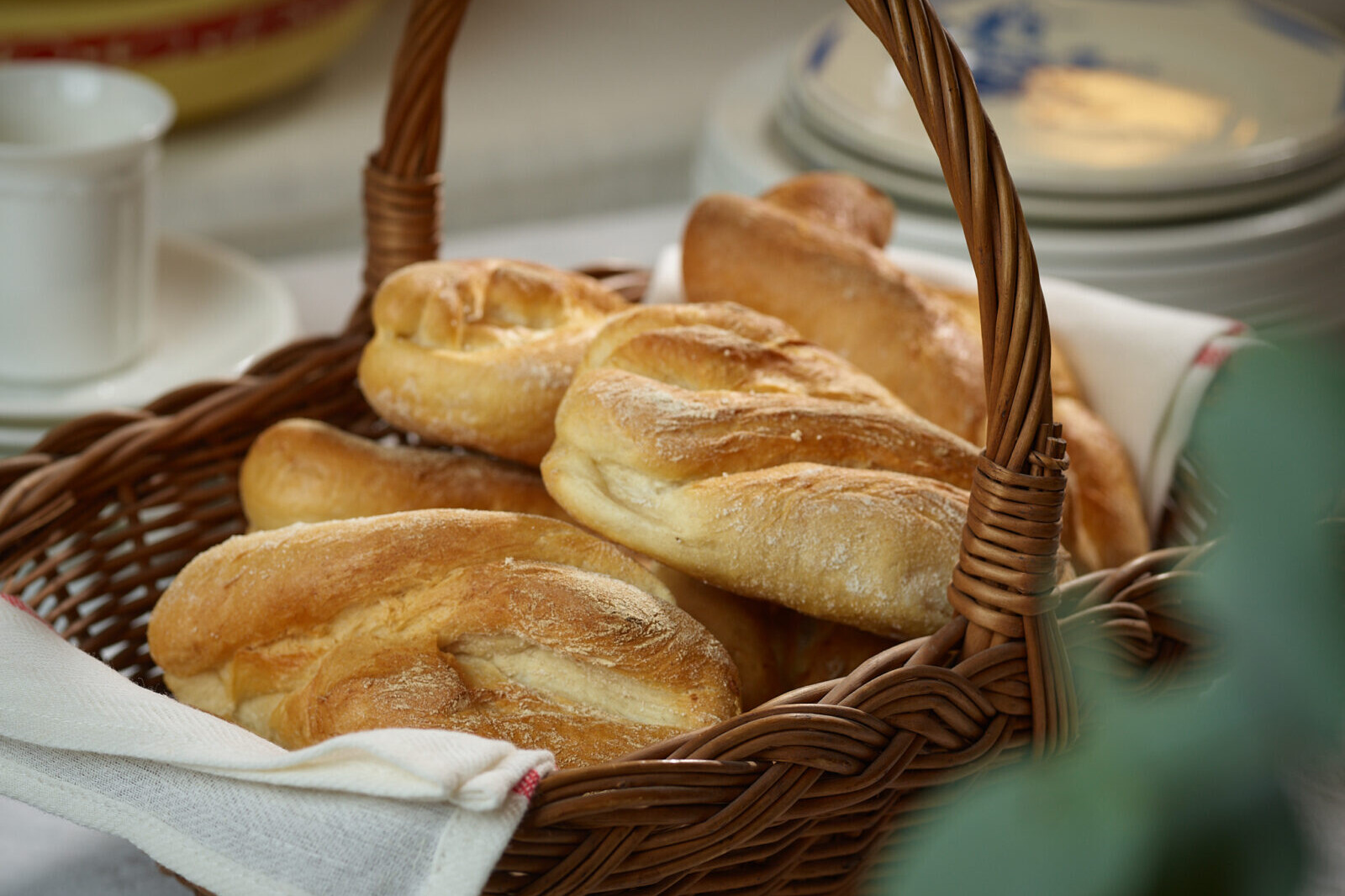 Fresh artisan baguettes in a wicker basket, rustic breads on a table with soft background bokeh