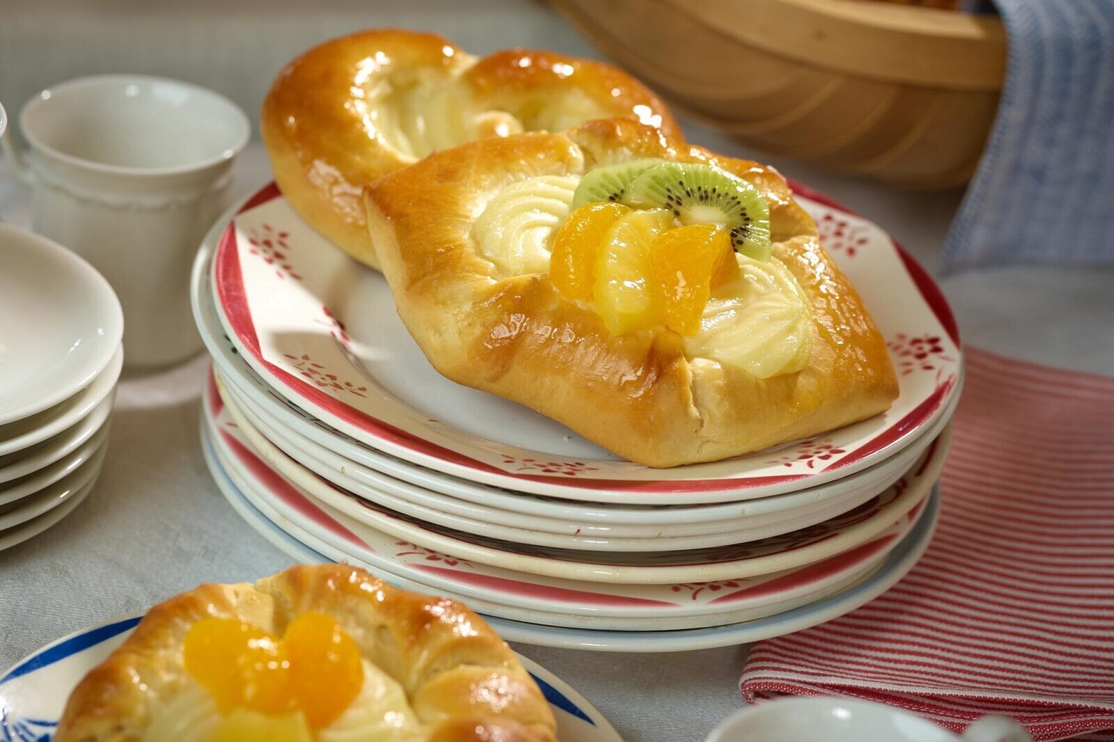 Glazed fruit bread rolls with kiwi topping on red-pattern plates, served for breakfast or brunch
