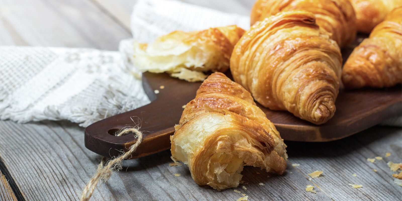 Freshly baked croissants on a wooden board, showcasing their golden, flaky layers. Perfect breakfast pastry.