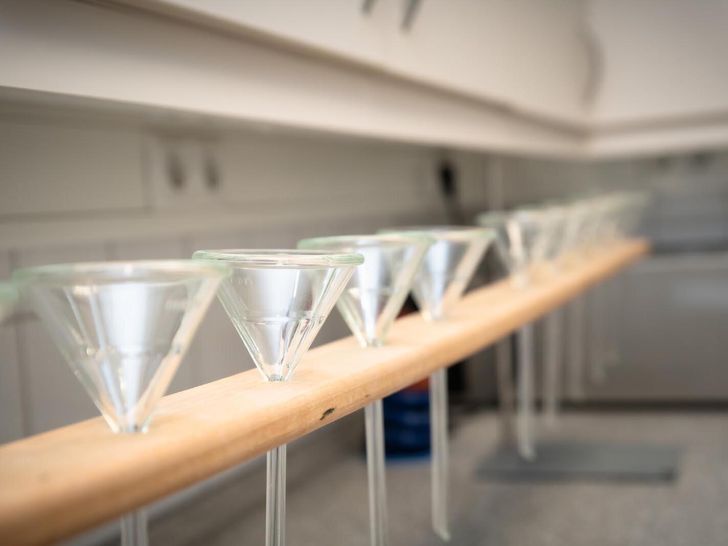 Martini glasses arranged on wooden railing in blurred bar interior, ready for drinks at a home party