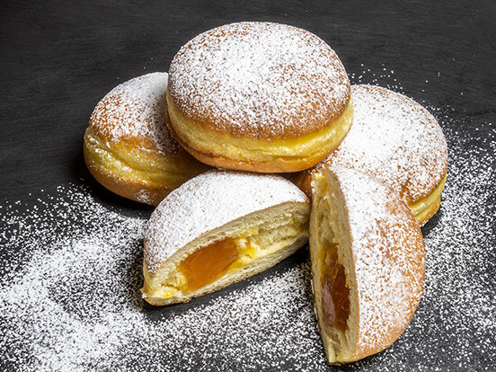 Powdered sugar filled pastries on slate, golden custard cream filling—close-up dessert photo