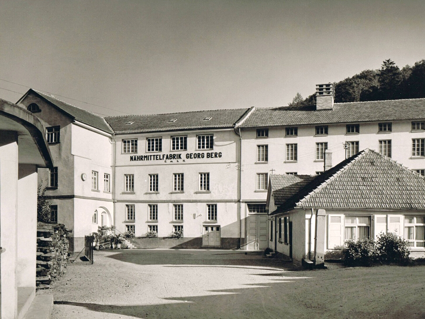 Historic food factory building with Nährmittelfabrik Georg Berg signage, nestled in a scenic countryside setting.