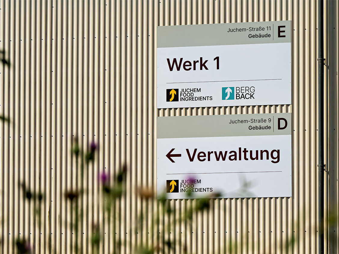Signs on a corrugated metal wall directing to Werk 1 and Verwaltung at Juchem Food Ingredients, Berg Back.